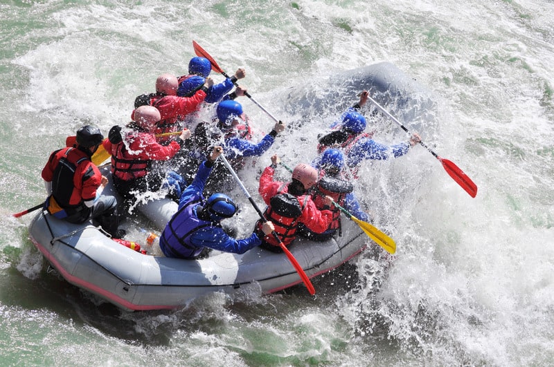A team building exercise with a group of people white water rafting through wild river rapids